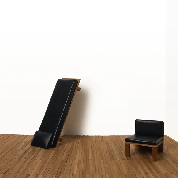 Interprétation Renversante de Pablo Reinoso: un fauteuil et un banc sur un plancher, avec le banc incliné, s’appuyant contre un mur blanc